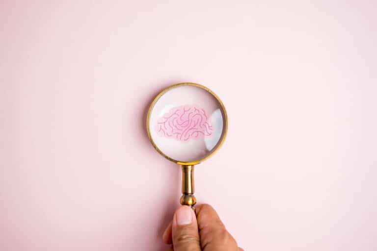 Concept illustration of a hand holding a magnifying glass over a drawing of a human brain