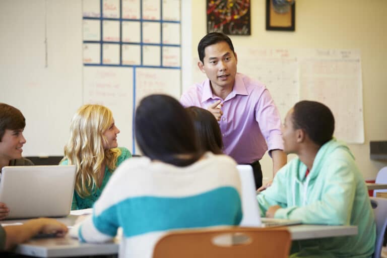 A male high school teacher speaking with students